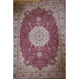 A red ground Kashmir rug with an all over ivory floral medallion design, 89" x 62"