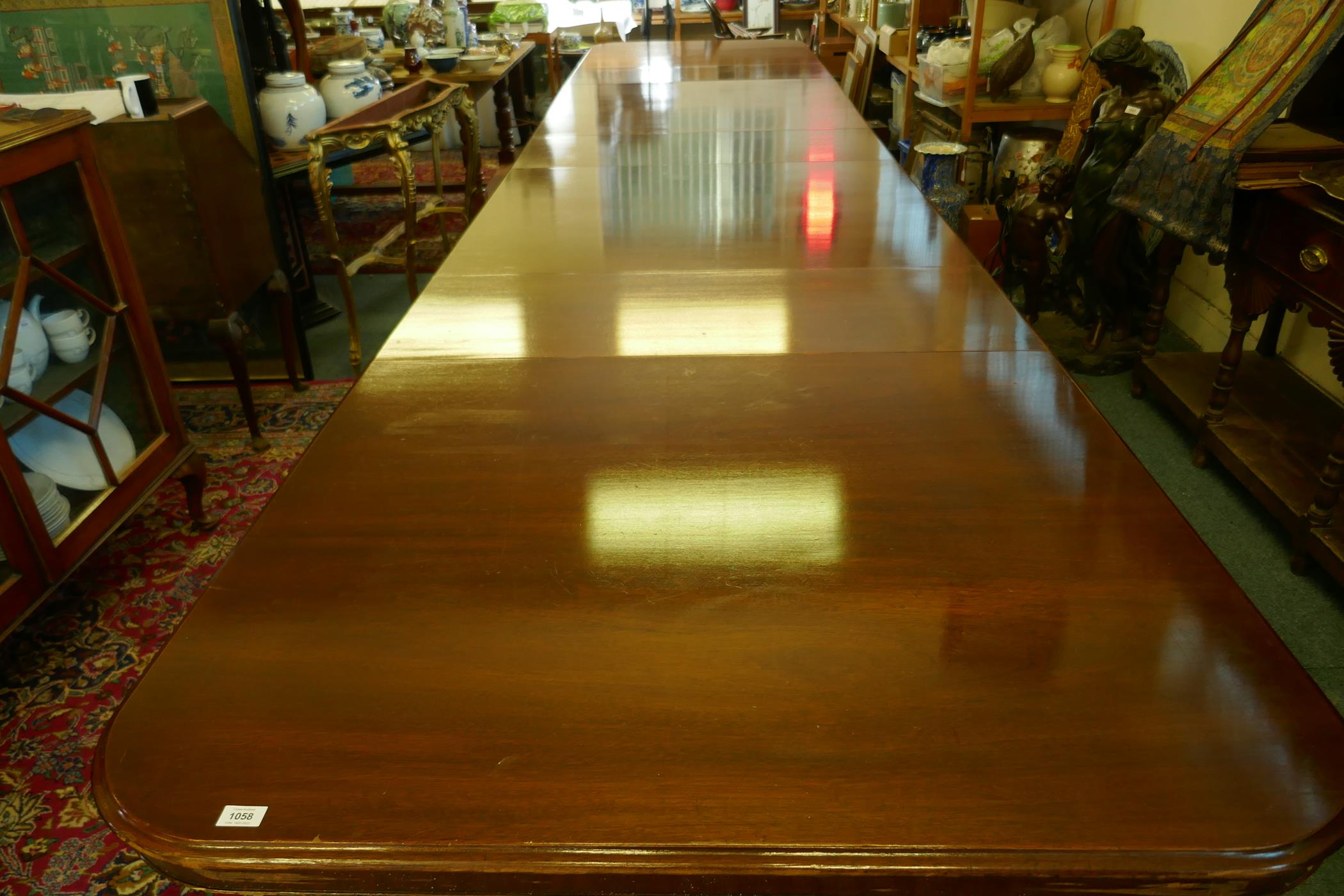 A Regency style mahogany four pedestal dining table with three extra leaves, the solid top with