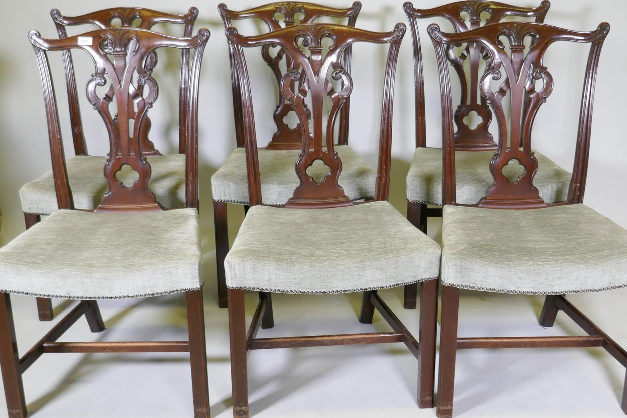 A set of six Chippendale style mahogany dining chairs with carved and pierced splats and overstuffed