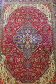 A large red ground Persian Tabriz carpet with geometric medallion design, 99" x 137", AF repairs