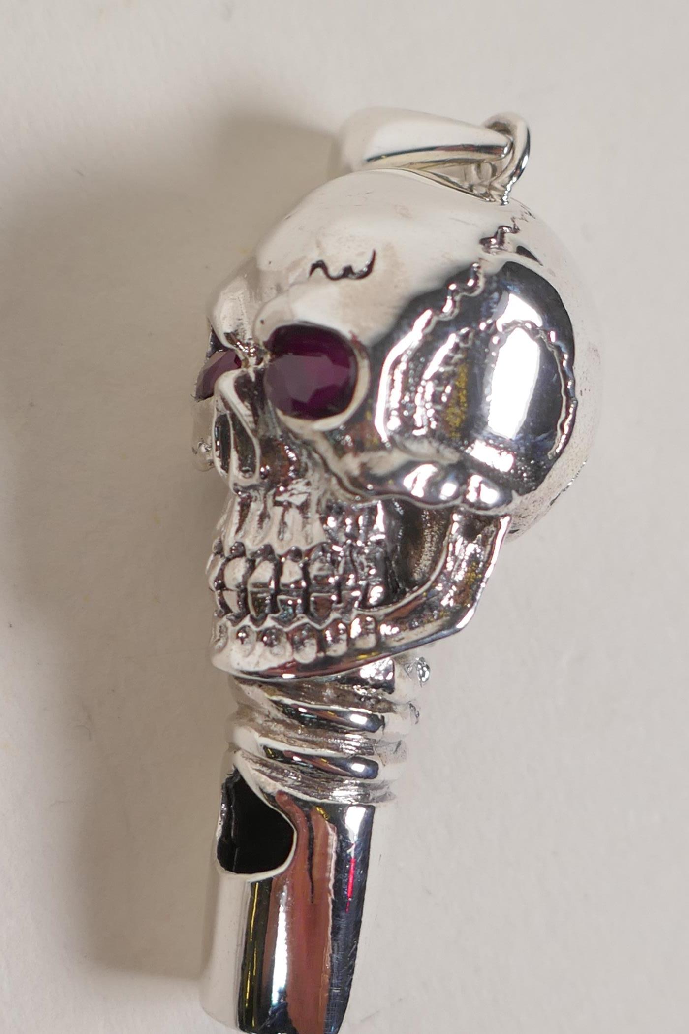 A sterling silver whistle modelled as a skull with ruby eyes