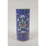 A Chinese polychrome porcelain cylinder vase with scrolling lotus flower decoration on a blue
