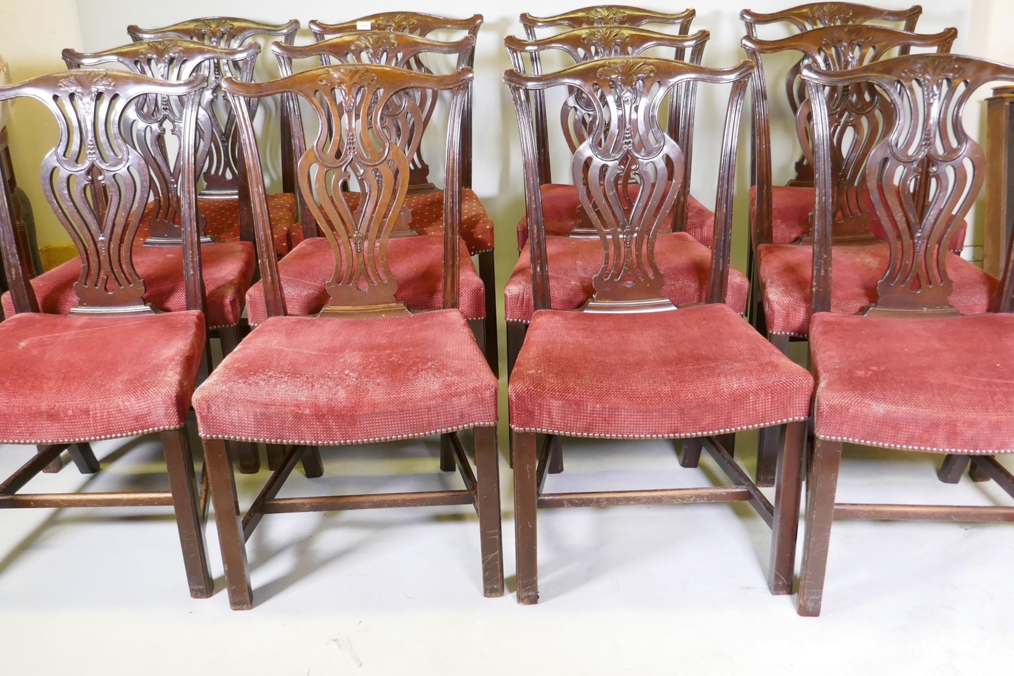 A set of twelve Chippendale style mahogany dining chairs with pierced and carved splat backs over