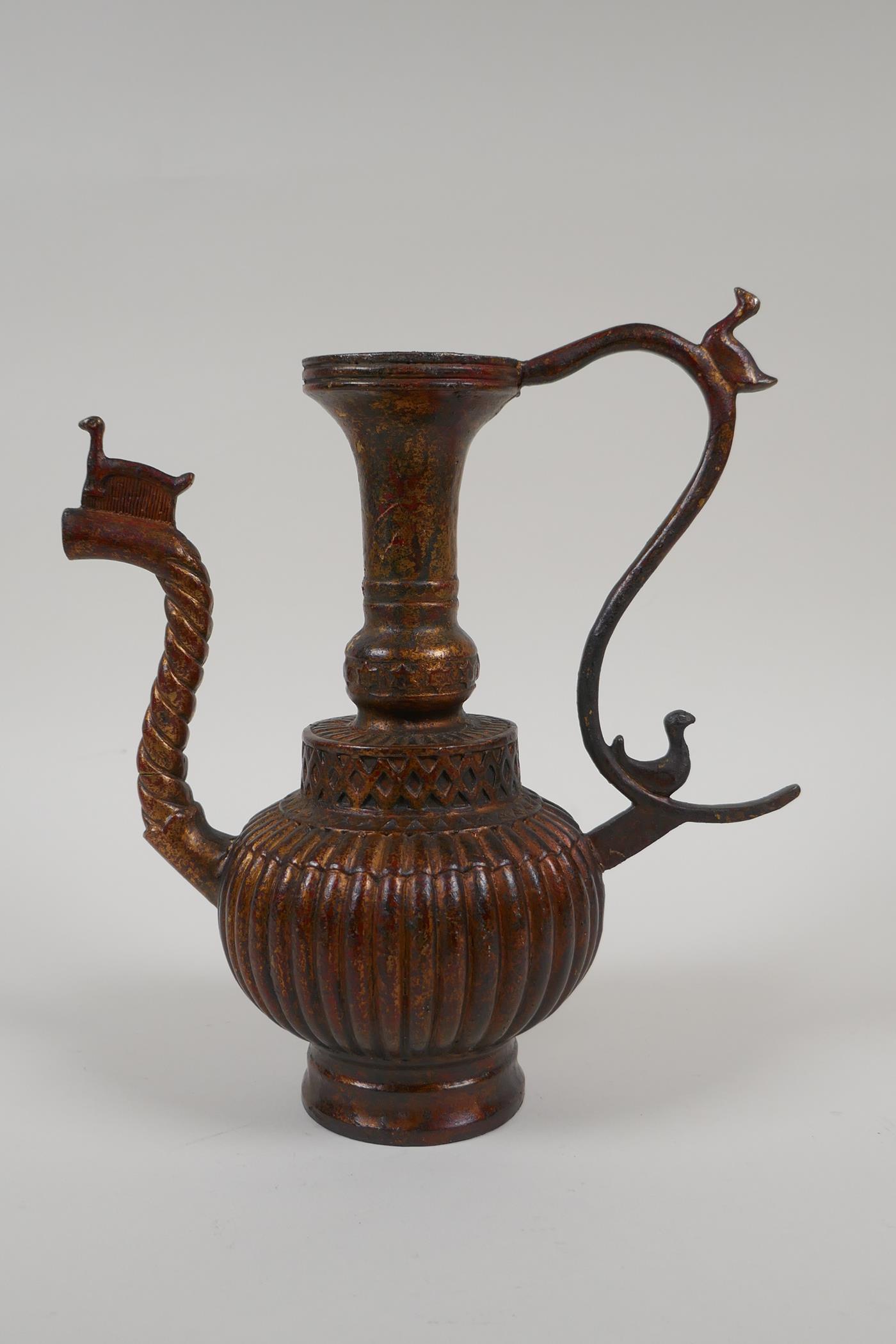 An Islamic gilt bronze ewer with a ribbed body, 9" high, spout AF
