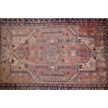 A Persian faded red ground wool rug with floral medallion design and blue borders, 90" x 57"