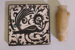 An antique Islamic tile, with glazed decoration depicting a peacock, cracked, 6" x 6", and alabaster