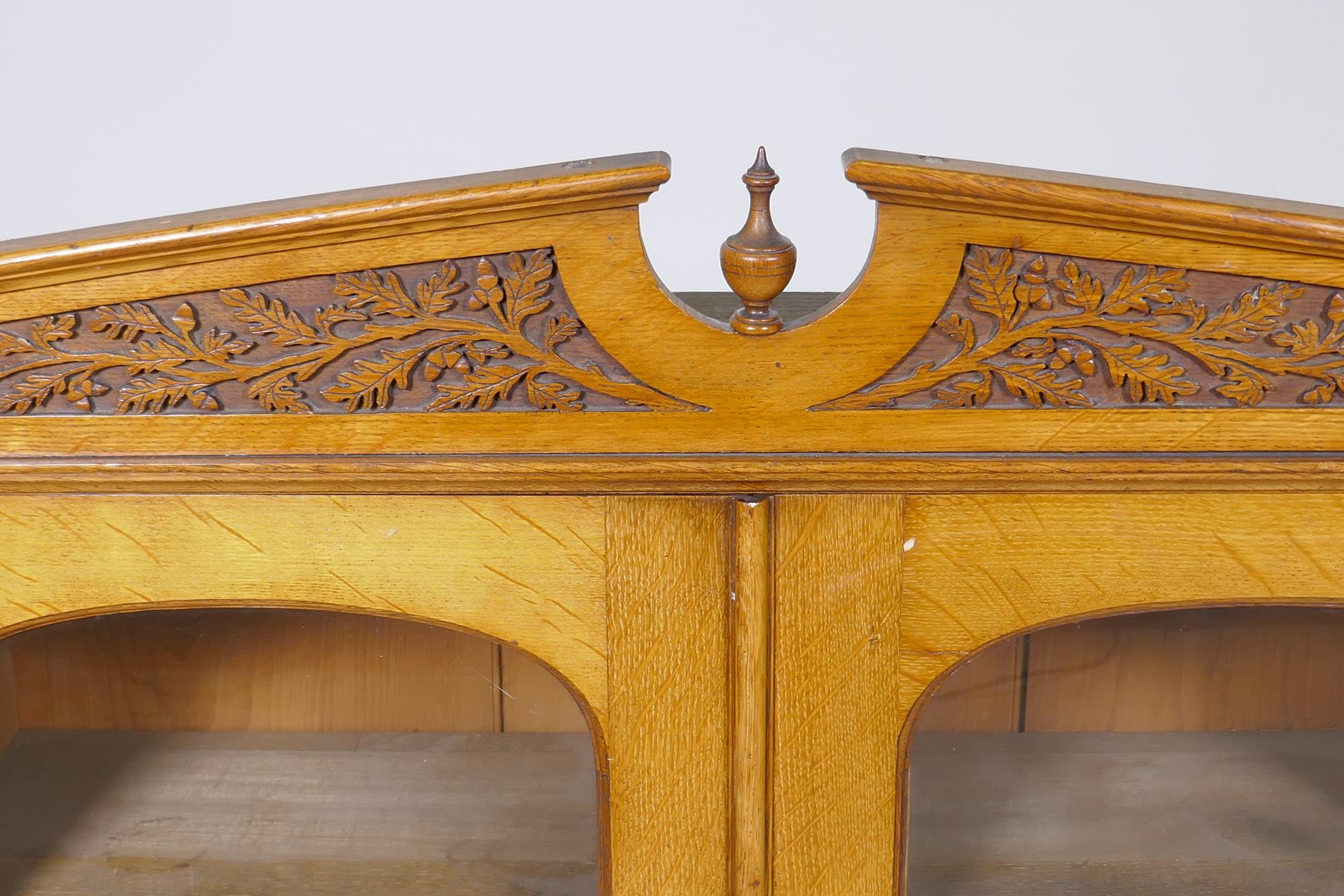 A Victorian golden oak cabinet, with carved oak and acorn pediment and two arched glazed doors, - Image 2 of 3