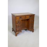 A Georgian style figured mahogany kneehole desk of eight drawers and centre cupboard, with leather