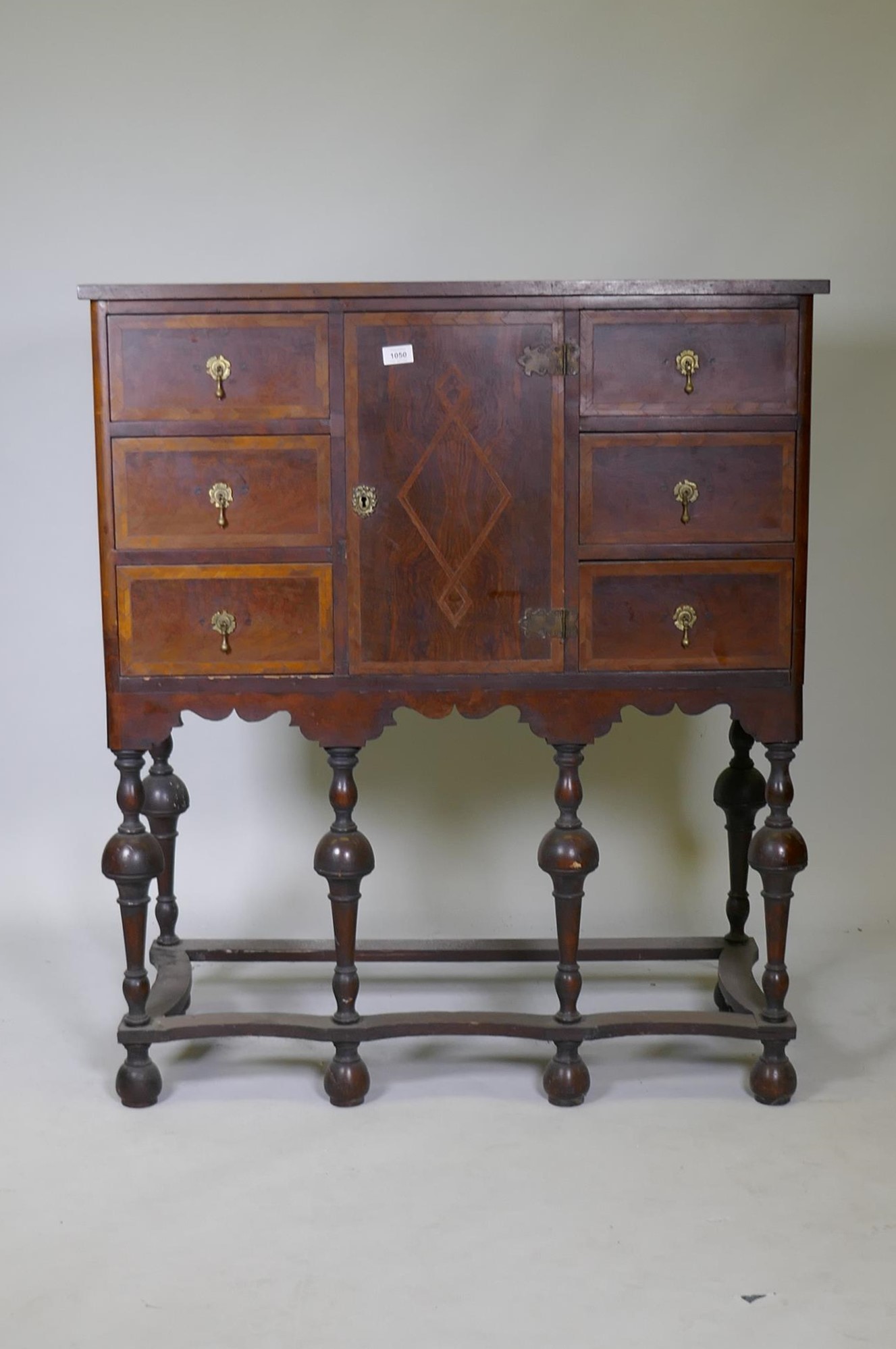 A C19th walnut cabinet on stand, with feather banded inlaid decoration, six drawers and central