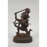 A Tibetan bronze figure of a deity standing over a figure bearing a knife, with the remnants of gilt