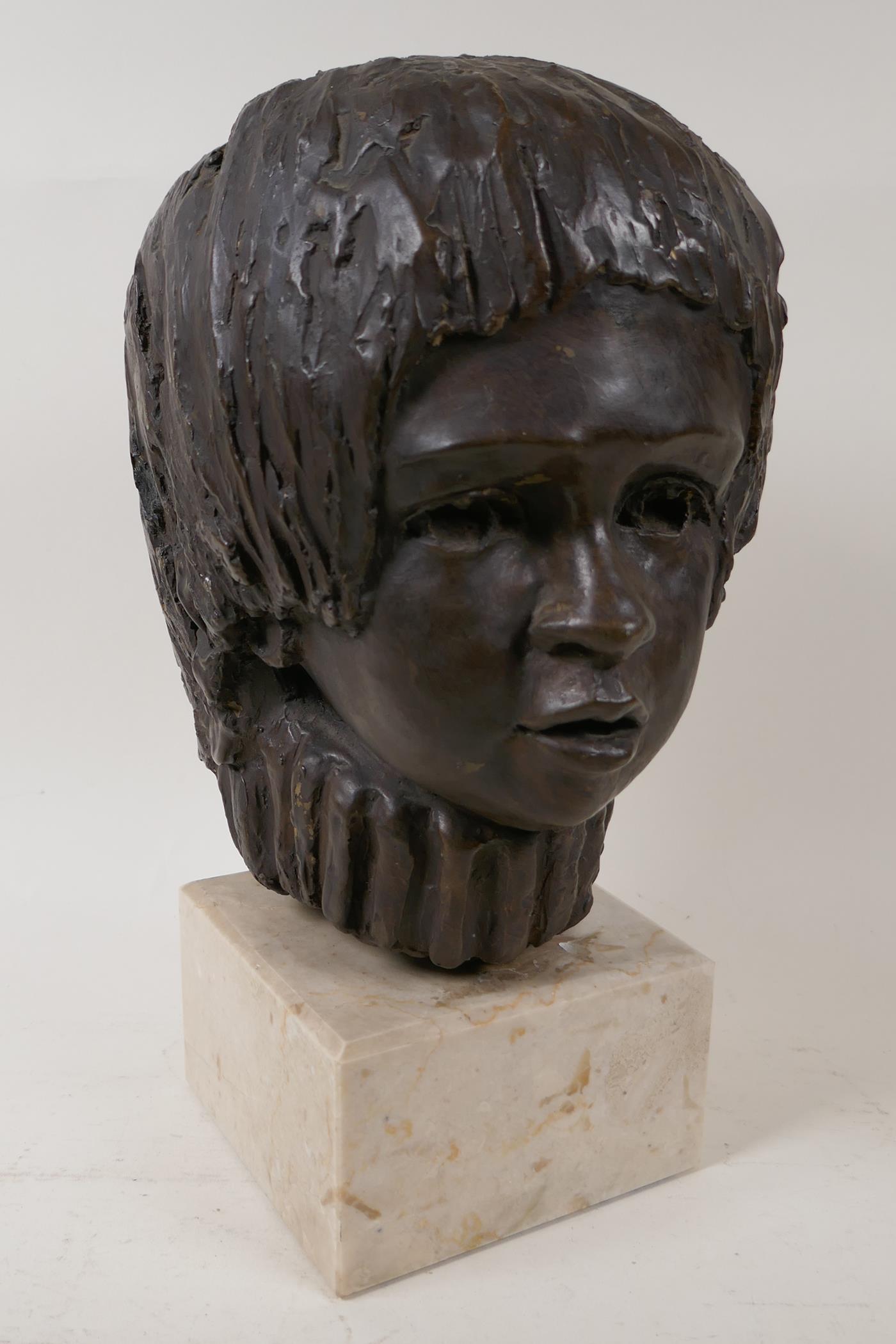 A bronzed composition bust of a child's head, on a square stone plinth, signed, 13" high