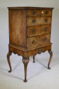 An antique walnut chest on stand, quarter veneered top with ogee edge over two and three drawers,