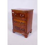A yew wood three drawer bow front bedside chest of drawers with brass drop handles, 25" x 19" x 14"