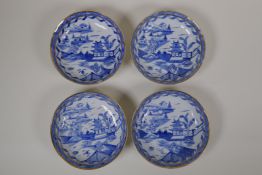 Four blue and white porcelain saucers with shaped rims, gilt bands and riverside decoration, 3½"