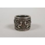 A Chinese white metal archers thumb ring decorated with figures on a revolving cuff, impressed