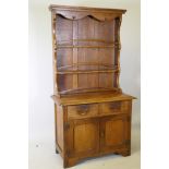A Cotswold School style Arts & Crafts oak cottage dresser of small proportions, the rack with shaped