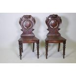 A pair of C19th mahogany hall chairs with carved crest shaped backs and bow front seats, raised on
