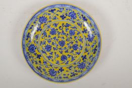 A Chinese Ming style yellow ground porcelain dish decorated with a blue and white scrolling lotus