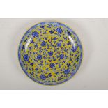 A Chinese Ming style yellow ground porcelain dish decorated with a blue and white scrolling lotus