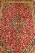 A full pile rich pink ground Persian carpet, hand woven with floral medallion design and blue
