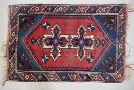 A red ground Persian wool rug with blue medallion design, 48" x 31"
