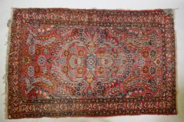 A Persian red ground wool rug with a floral design, AF worn, 51" x 80"