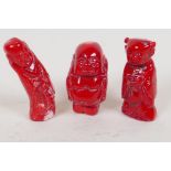 Three small carved coral coloured stone figures of Buddha, 2½" high