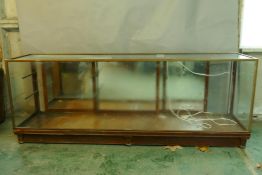 A vintage brass and mahogany shop display cabinet with mirrored back, bears maker's label Harris &