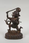 A Tibetan bronze figure of a deity standing over a figure bearing a knife, with the remnants of gilt