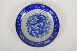 A Chinese crackleware dish with blue and white dragon decoration to the centre and prunus blossom to