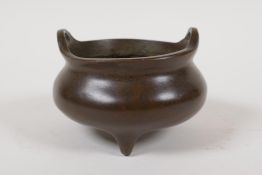 A Chinese bronze censer with two phoenix eye handles and tripod supports, impressed 4 character mark