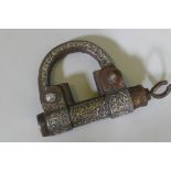 A Middle Eastern cast iron padlock with raised decoration in white and yellow metals and Islamic