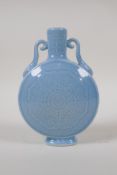 A blue glazed porcelain moon flask with two handles and underglaze stylised lotus flower decoration,
