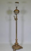 A Victorian brass standard lamp with fluted column and shaped base, retaining its original oil