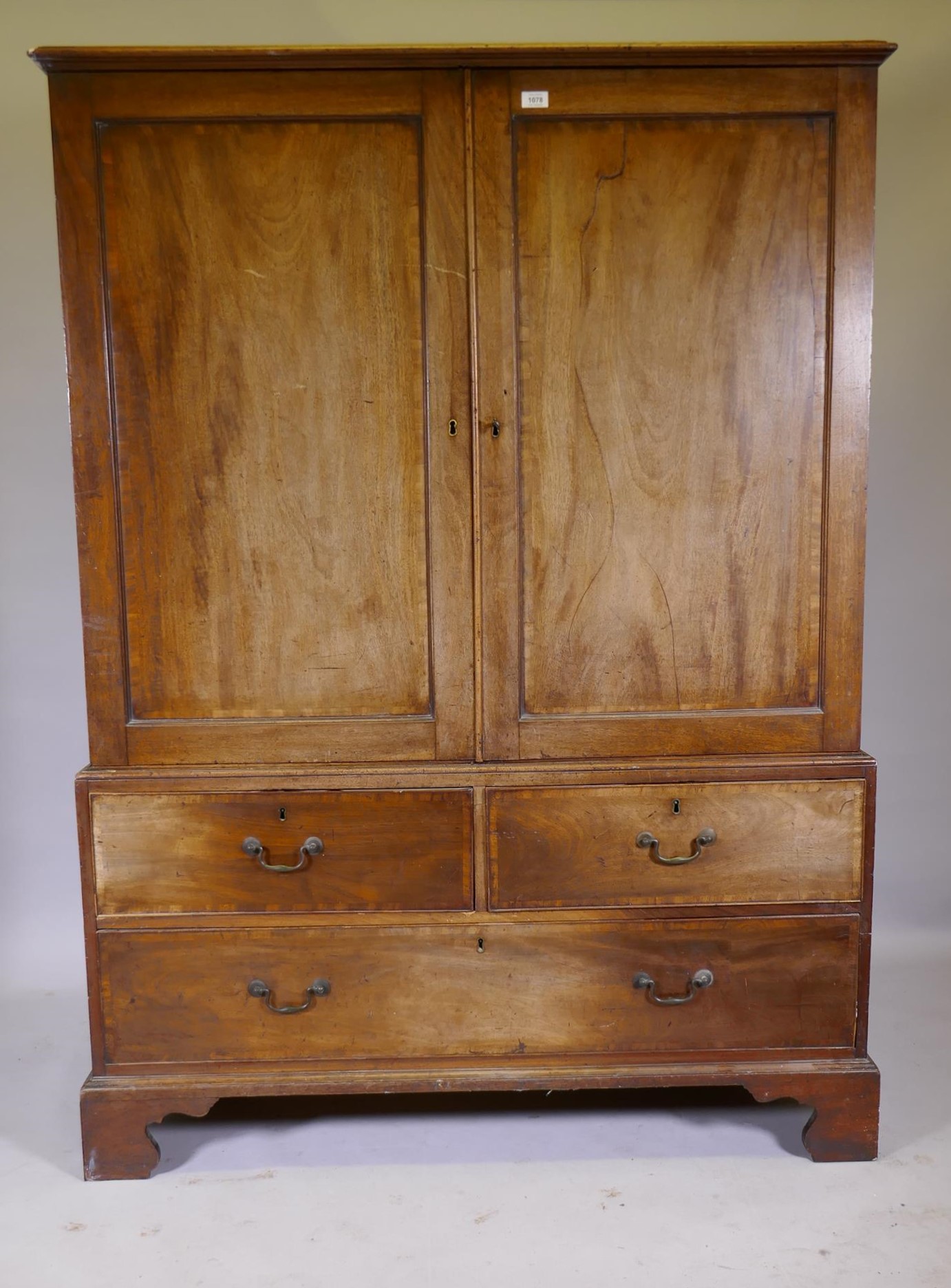 A George III mahogany linen press of small proportions, the doors and drawers with crossbanded inlay