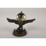 A brass ball desk clock mounted on a bronzed metal eagle stand, 7" wide