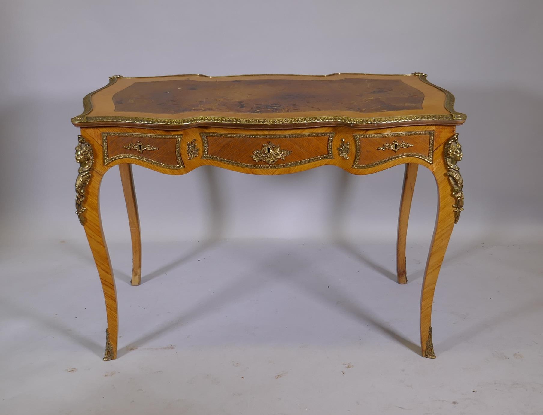 A Louis XV style inlaid tulipwood and brass mounted writing table, with inset leather top and three