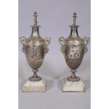 A pair of silver plated urns with raised classical decoration and satyr mask handles, raised on
