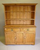 A Victorian pine dresser with enclosed rack and two shelves, the base with two drawers over two