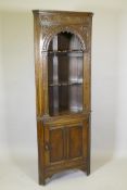 An Ipswich oak corner cupboard with carved decoration and open shelves over a panelled door, 27" x