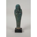 An Egyptian turquoise glazed faience shabti, mounted on a display base, 7" high