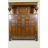 A Harrods Jacobrean style oak court cupboard with carved frieze and cupboard over two drawers and