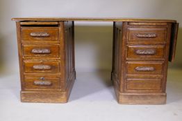 An Edwardian seven drawer oak panelled desk, the top with fold out flap, 55" x 32" x 30"