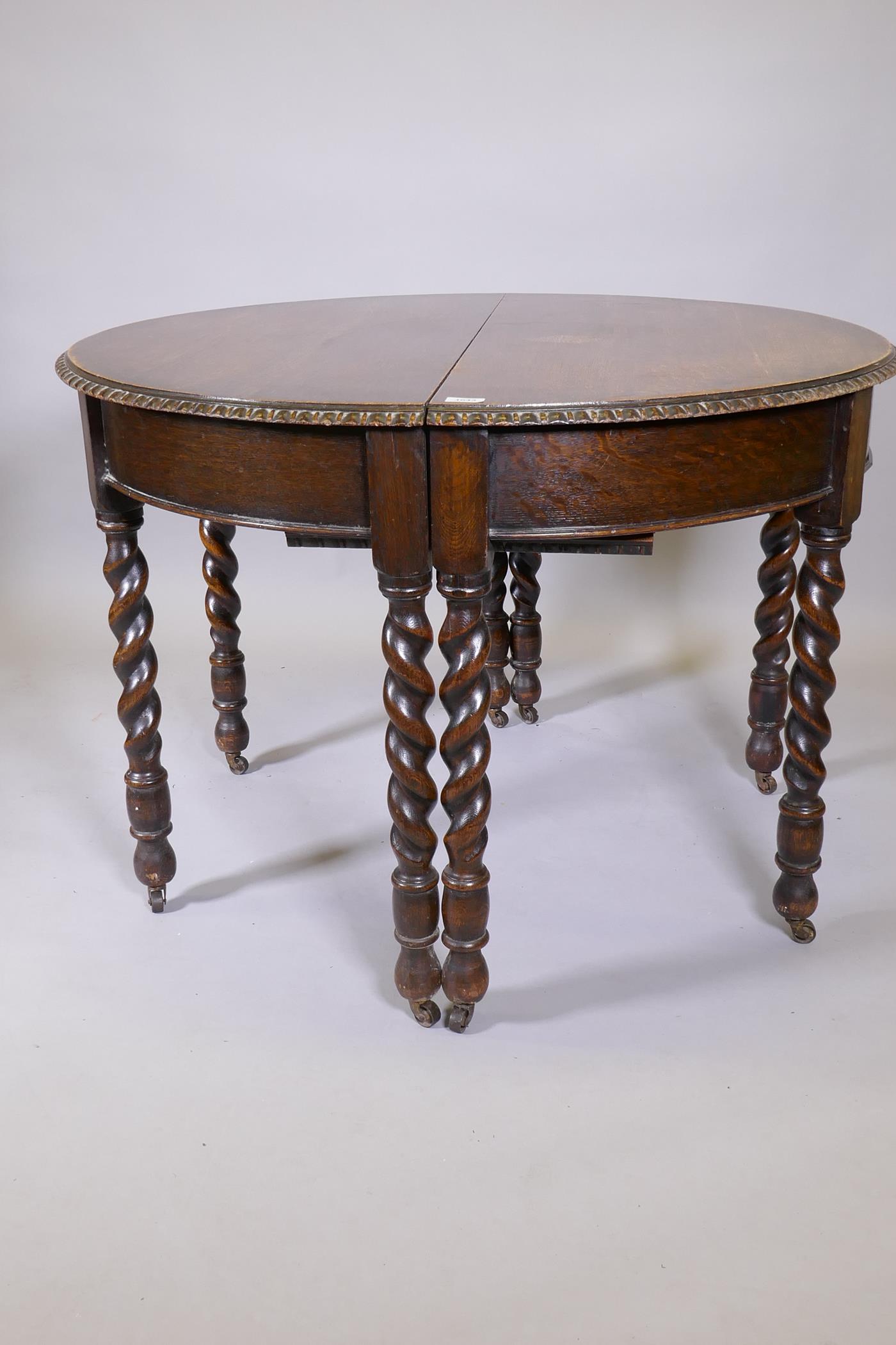 An early C20th oak wind out dining table, raised on eight handed barleytwist supports, with extra