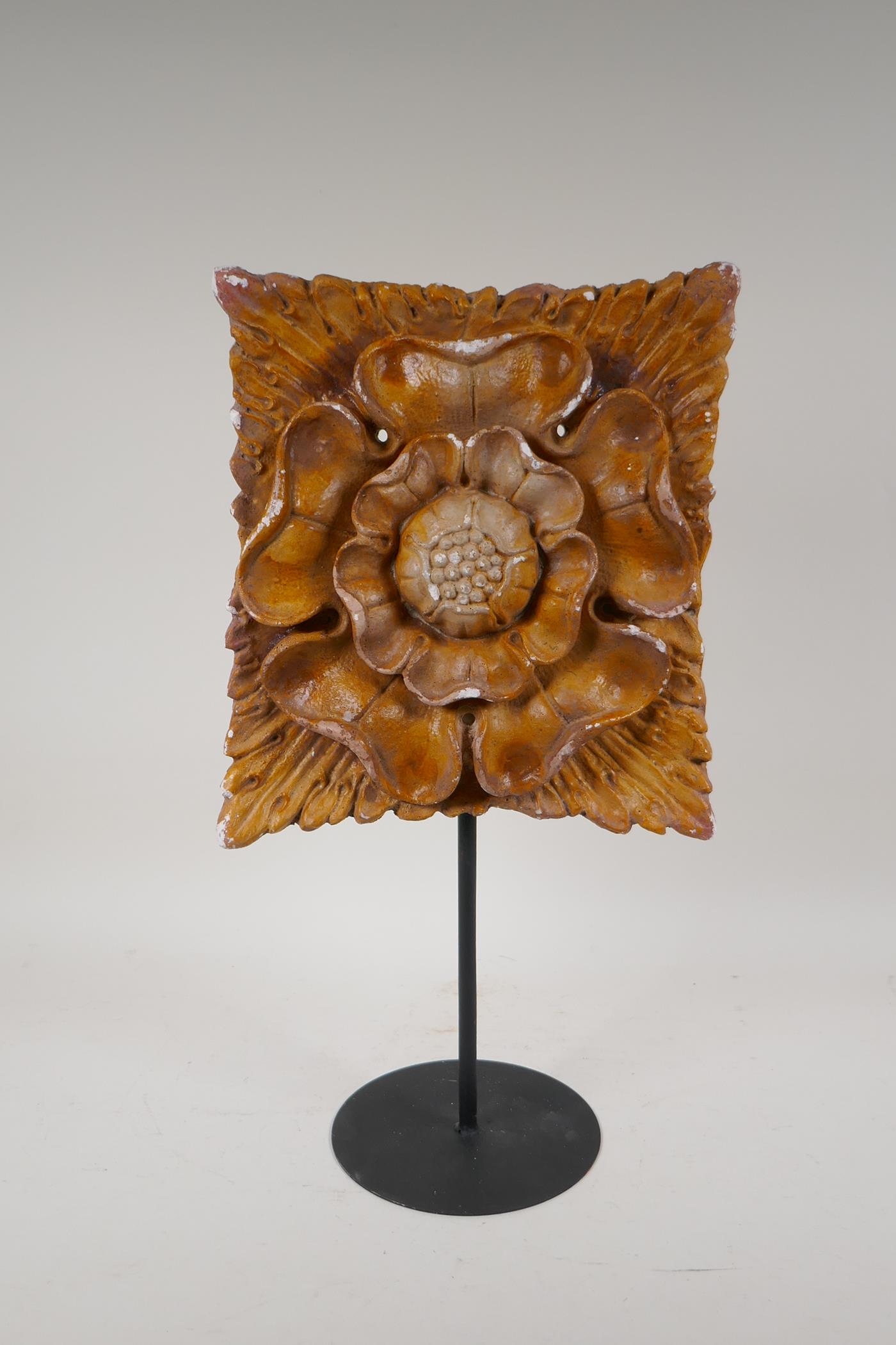 A painted plaster Tudor Rose plaque on a display stand, 18½" high, plaque 10" x 10"