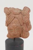 An Eastern terracotta head, 3" long, on turned stand