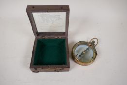 A brass cased map reader compass, 3" diameter, in a wood and glass box