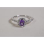 A 9ct white gold ring set with a central amethyst encircled by diamonds, with diamond shoulders,