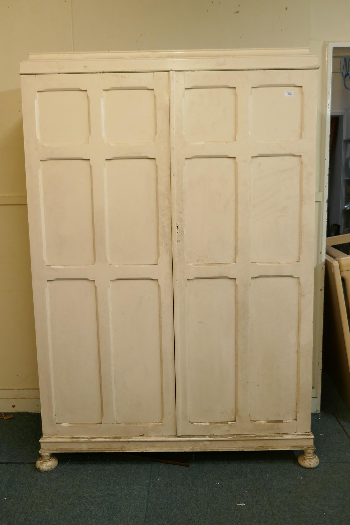 A 1930s painted oak Jacobean style wardrobe, with fitted interior, raised on squashed bun