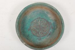 An Islamic metal shallow bowl, the centre engraved with a symbol, 5" diameter